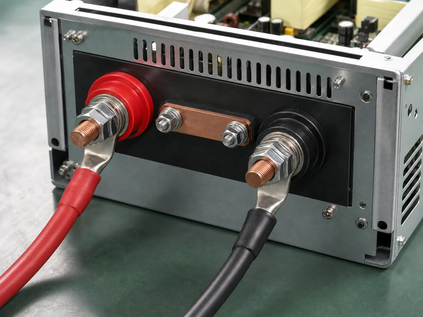 Power supply rear terminal section with red and black high-current posts, copper bridge, and cable lugs